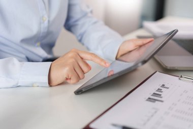 İş konsepti, iş kadını ofisteki tabletteki pazarlama verilerini araştırıyor ve kontrol ediyor.