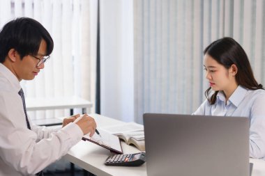 İş konsepti: İki iş arkadaşı projedeki yatırımı açıklayan belgeye işaret ediyor.