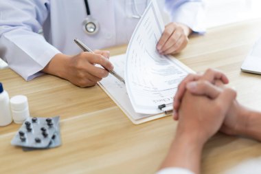Hastasının semptomlarını dinlerken bir doktorun sağlık durumunu değerlendirmesi.