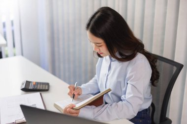 İş konsepti: İş kadını yeni bir projeye hazırlanmak için kitapta yatırım verilerini okuyor.