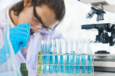 Laboratuvar araştırma konsepti. Laboratuvarda çalışan bilim adamı araştırma için çözeltiyi tüpe koyuyor..