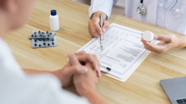 Doktor konseptini ziyaret ediyorum. Doktorun önerdiği bir hasta, tedavi için beyaz şişeye ilaç koymasını öneriyor.