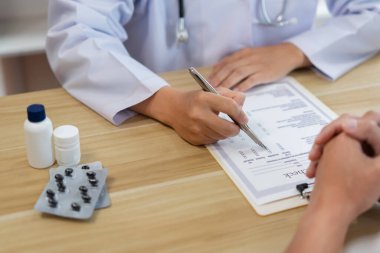 Hastasının semptomlarını dinlerken bir doktorun sağlık durumunu değerlendirmesi.