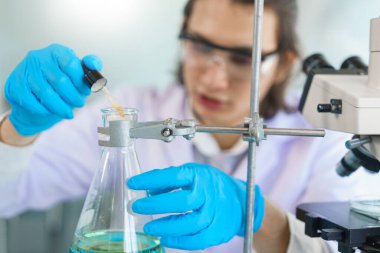 Laboratuvar araştırma konsepti. Aşı araştırması için bilimadamı çözeltiyi deney kabına bırakıyor..