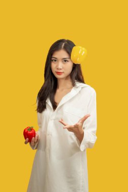 Vejetaryen konsepti, sağlıklı kadın izole edilmiş sarı arka planda renkli dolma biber kusuyor..