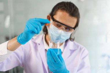 Laboratuvar araştırma konsepti. Aşı araştırması için bilimadamı çözeltiyi deney kabına bırakıyor..