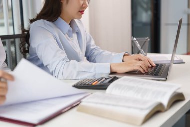 İş konsepti, iki iş arkadaşı mali verileri kontrol ediyor ve dizüstü bilgisayardan rapor yazıyor.