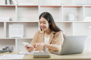 Çevrimiçi yaşam tarzı konsepti. Bir kadın işçi, kağıdındaki çizelgelere göre toplam satışı hesaplıyor.