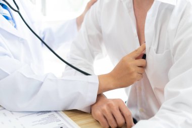 Bir doktor konseptini ziyaret ediyorum. Bir hasta kıpırdamadan oturuyor ve göğsünde bir doktor tarafından muayene ediliyor.