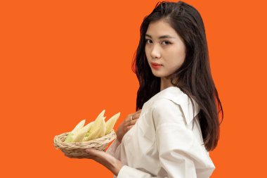 Vejetaryen konsepti, sağlıklı bir kadının elinde mısır septi, izole edilmiş turuncu arka plan..