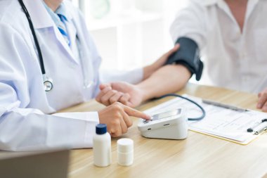 Doktor konseptini ziyaret etmek. Doktorun, hastanın kolundaki kan basıncını ölçmek için kullandığı aleti kullanması.
