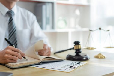 Hukuk danışmanlığı kavramı. Bir erkek savcı sözleşmesini kontrat kağıdına yazmadan önce kendi defteriyle gözden geçirir. 