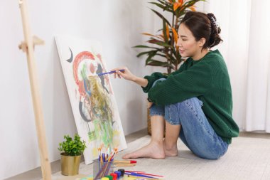 Sanat konsepti, genç Asyalı kadın sanat stüdyosunda resim çizmek için yerde oturuyor..
