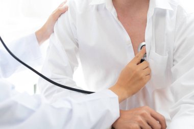 Bir doktor konseptini ziyaret ediyorum. Bir hasta kıpırdamadan oturuyor ve göğsünde bir doktor tarafından muayene ediliyor.