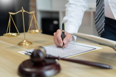 Hukuk danışmanlığı kavramı. Bir erkek avukat, sözleşmeye kendi başına daha net bir açıklama ekleyerek bazı detayları açıklığa kavuşturuyor.  