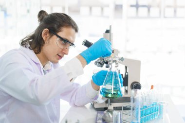 Laboratuvar araştırma konsepti. Aşı araştırması için bilimadamı çözeltiyi deney kabına bırakıyor..