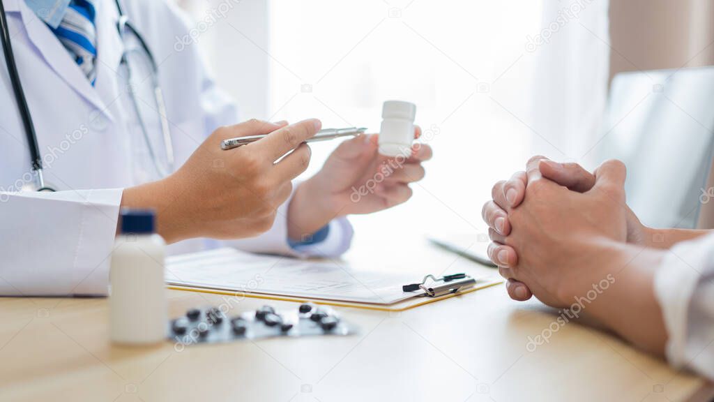 Visiting a doctor concept A patient being suggested how to take a pill in the white bottle for treatment