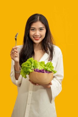 Vejetaryen konsepti, sağlıklı bir kadın taze sebze kasesinde doğranmış marul ve mor lahana yer..