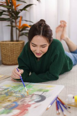 Sanat konsepti, genç Asyalı kadın yerde yatıyor ve sanat şaheserini resmetmeye çalışıyor..