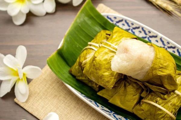 Tayland tatlısı konsepti, ahşap masa üzerinde yapış yapış pirinçli muzdan yapılmış Khao Tom paspası..