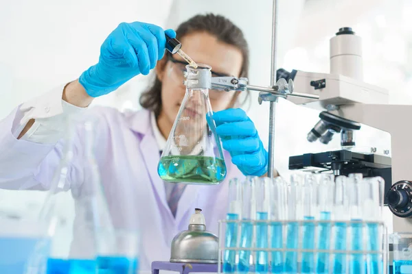 Laboratuvar araştırma konsepti. Aşı araştırması için bilimadamı çözeltiyi deney kabına bırakıyor..