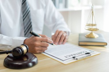 Hukuk danışmanlığı kavramı. Bir erkek savcı, sözleşmenin yeni versiyonunu masasında baştan sona okuyor.