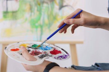Sanat konsepti yaratıcılığı, Asyalı genç bir kadının eli boya fırçasını palete batırmak için tutar..