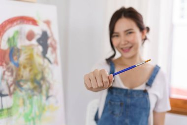 Sanat konsepti, genç Asyalı kadın resim çizmek için boya fırçası tutuyor..