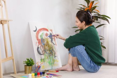 Sanat konsepti, genç Asyalı kadın sanat stüdyosunda resim çizmek için yerde oturuyor..