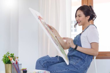 Sanat yaratıcılığı, genç Asyalı kadın resim çizmek için stüdyoda oturuyor..