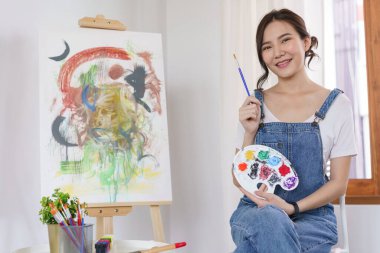 Sanat konsepti, genç Asyalı kadın resim çizmek için boya fırçası ve renk paleti tutuyor..