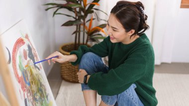 Sanat konsepti, genç Asyalı kadın sanat stüdyosunda resim çizmek için yerde oturuyor..