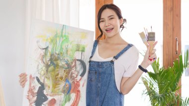 Sanat konsepti, genç Asyalı kadın sanat eseri ve boya fırçası tutuyor..