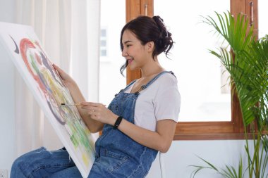 Sanat yaratıcılığı, genç Asyalı kadın resim çizmek için stüdyoda oturuyor..