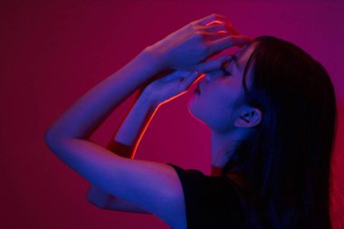 Moda ve güzellik anlayışı. Moda kadını, neon ışıklı arka planda poz vermek için el kullanır..