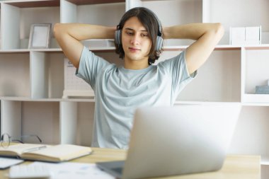 Uzaktan eğitim kavramı, genç çocuk müzik dinler ve internetten sıkı çalıştıktan sonra rahatlamak için esner..