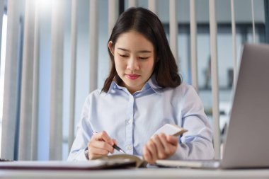 İş konsepti: İş kadını yeni bir projeye hazırlanmak için kitapta yatırım verilerini okuyor.