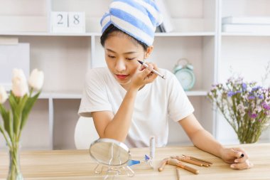 Ev rahatlama konsepti, duştan sonra türbanlı genç bir kadın ve makyaj için göz kapağına göz kalemi sür..