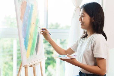 Sanat konsepti, Asyalı kadın sanatçının resim stüdyosunda tuval üzerinde fırça kullanması..