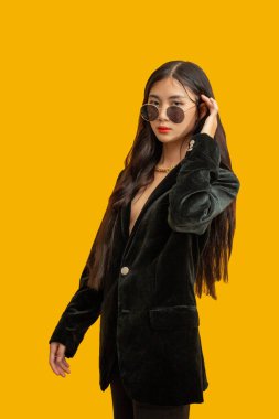 Moda konsepti: Stüdyoda siyah pantolon ve güneş gözlüğü takan şık bir kadın..
