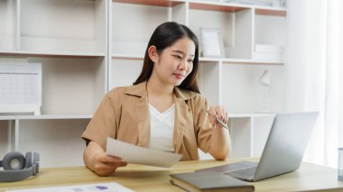 Çevrimiçi yaşam tarzı konsepti: Çalışan bir kadın, kağıt işlerinde ve defterde kaçırdığı ayrıntıları belirtmek için enerjik davranır.