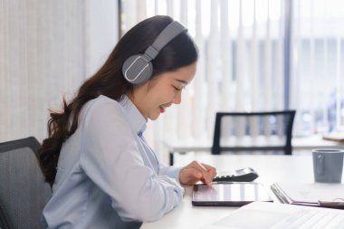 İş konsepti, kulaklıklı iş kadını müzik dinleyecek ve tablet üzerindeki mali raporları kontrol edecek.