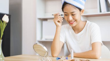 Ev rahatlama konsepti, duştan sonra türbanlı genç bir kadın ve makyaj için göz kapağına göz kalemi sür..