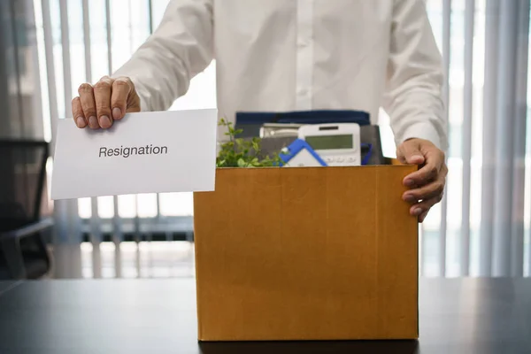 Concept of leaving job, Male employee holding box of personal belonging and resignation letter.