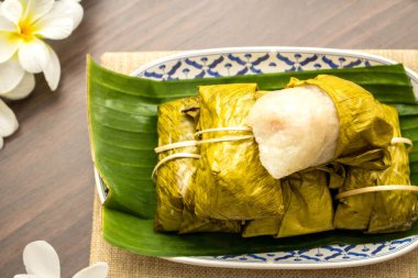 Tayland tatlısı konsepti, ahşap masa üzerinde yapış yapış pirinçli muzdan yapılmış Khao Tom paspası..