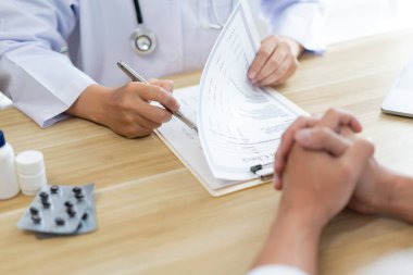 Hastalarının semptomlarını dinlerken bir doktorun sağlık durumunu değerlendirmesi.