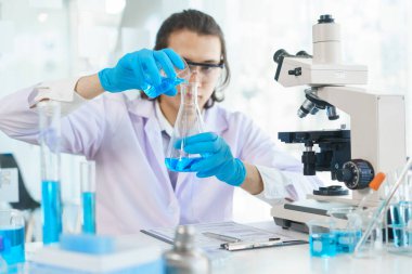 Laboratuvar araştırma konsepti, bilim adamı aşı ve uyuşturucu araştırması için beher içine çözeltisi döker..