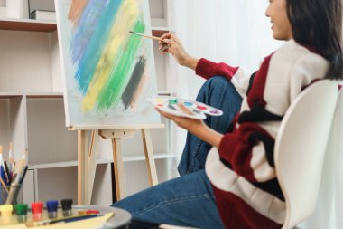 Sanat konsepti, resim yapmak için fırça ve renk paleti tutan Asyalı kadın sanatçı..