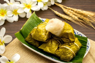 Tayland tatlısı konsepti, ahşap masa üzerinde yapış yapış pirinçli muzdan yapılmış Khao Tom paspası..