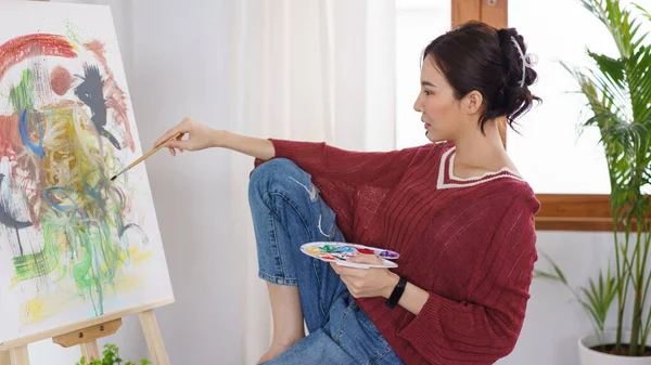 Creative of art concept, Young asian woman using paintbrush with color palette to drawing on canvas.
